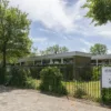 Vooraanzicht van dagbestedingslocatie Noorderkroonstraat in Dordrecht, met tuin en toegangshek.