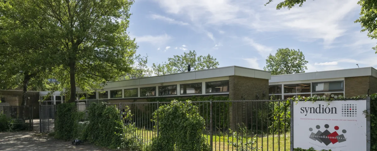 Vooraanzicht van dagbestedingslocatie Noorderkroonstraat in Dordrecht, met tuin en toegangshek.