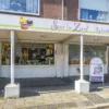 Gevel van een winkelpand met de naam “Syn in Zoet Ambachtelijke Bakkerij”, met etalages vol bakproducten en een stoepbord bij de ingang onder een overkapping.