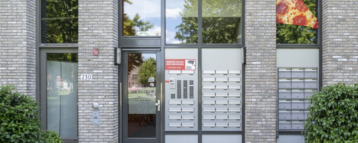Hoofdingang van woonlocatie Leerpark met toegangsdeur, intercom en brievenbussen.