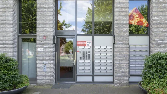 Hoofdingang van woonlocatie Leerpark met toegangsdeur, intercom en brievenbussen.