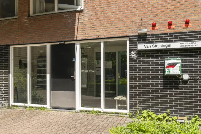 Entree van woongebouw Van Strijsingel met toegangsdeur, brievenbussen en een AED-kast aan de buitenmuur.